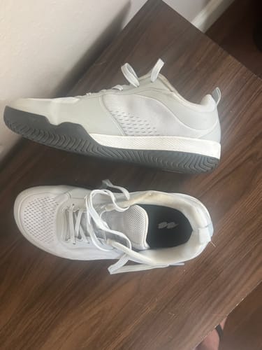 Customer's pair of white CUURT Muuv Court Shoes on a wooden surface, showing one from the side and one from above.