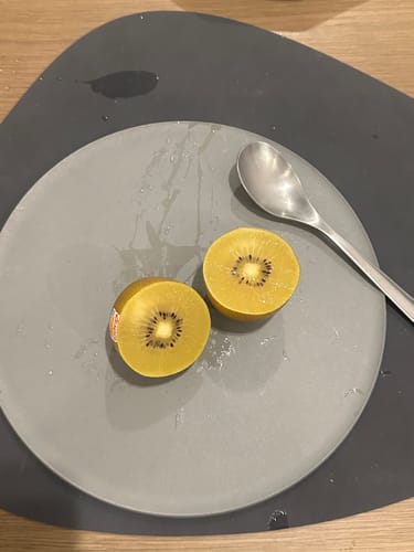 顧客的灰色CHOPLATE兩用砧板餐盤，上面放著切開的黃金奇異果和湯匙。