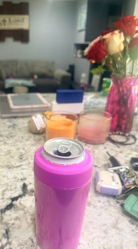 Close-up of a customer's pink Universal Buddy can cooler holding a can on a kitchen counter.