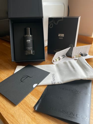 Customer's Lilium Blume Eau de Parfum in its open black box, surrounded by packaging and small sample vials on a table.
