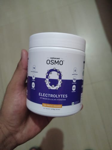 Customer holding a white tub of OSMO Electrolyte Hydration Blend in the Valencia Orange flavour.