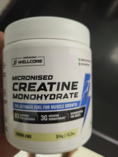 Customer holds up their white tub of Wellcore Micronised Creatine Monohydrate, showing the Lemon Lime flavor.
