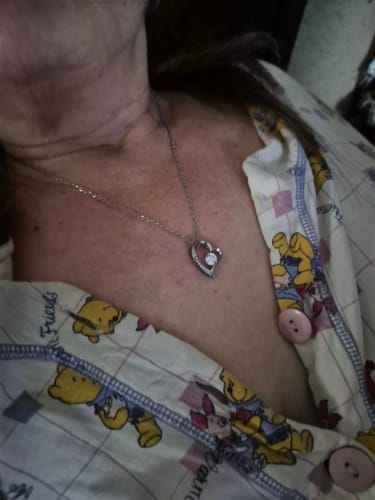 Close-up of a customer wearing the silver-colored, heart-shaped Forever Love Necklace from the gift set.
