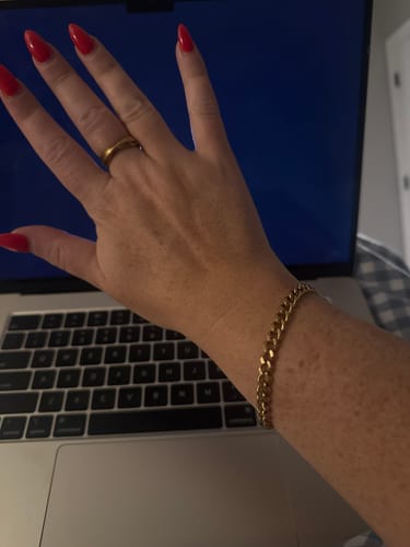 Customer's wrist wearing the gold Havana Shore Bracelet in front of a laptop.