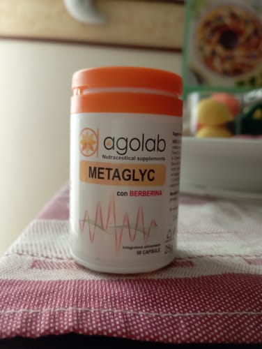 Un recensore mostra il flacone di Metaglyc con tappo arancione su un tavolo.