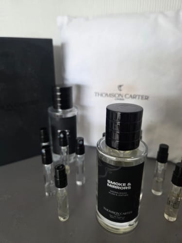 Customer's Smoke & Mirrors Eau de Parfum bottle shown with several sample vials and branded packaging.