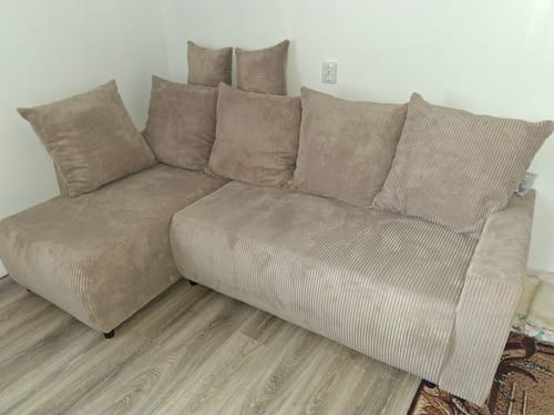 Kliento smėlio spalvos velvetinis minkštas kampas POLO su didelėmis pagalvėmis, pastatytas kambaryje.