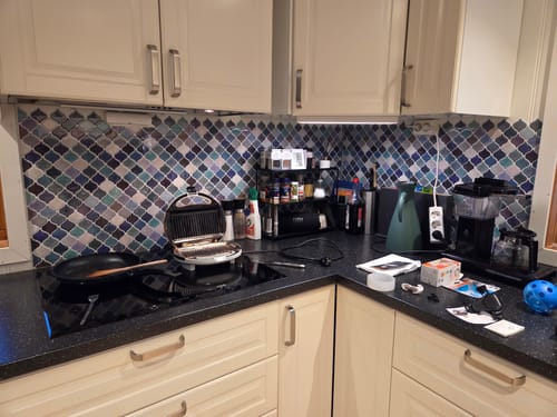 Anmelders kjøkken med blå og grønne Lanterne-fliser som backsplash bak en benkeplate med kjøkkenutstyr.