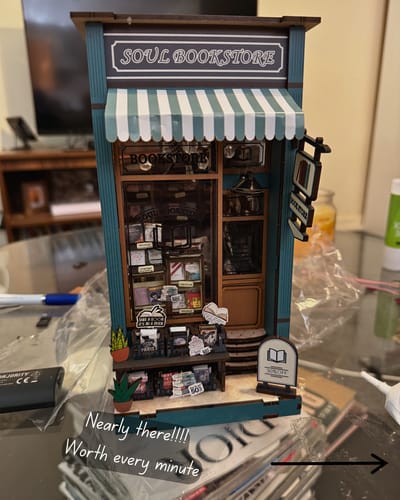 A customer's assembled Corner Bookstore kit, showing the teal miniature bookshop with a striped awning.