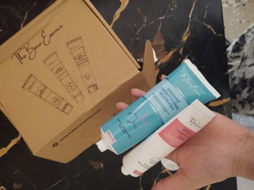 Reviewer holding the face wash and cream from the Eco Pigmentation Bundle in their hand, with the box behind.