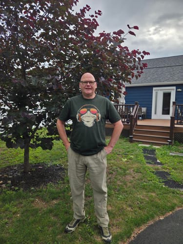 Customer wearing the dark green Amphibian Grooves t-shirt outdoors, showing the garment's comfortable fit and length.