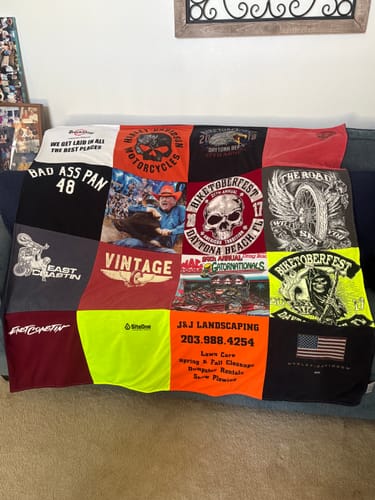 Customer's T-Shirt Quilt made from her late husband's colorful motorcycle t-shirts, spread on a couch.