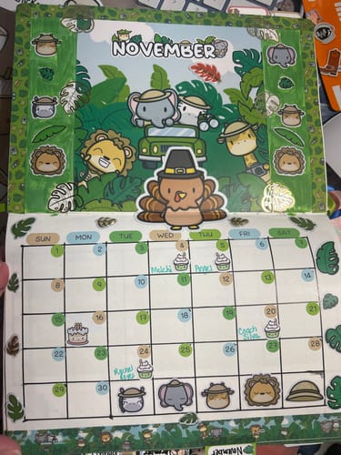 Customer's November planner spread decorated with the Planner Subscription kit, featuring cute safari animal stickers and bright green leaves.
