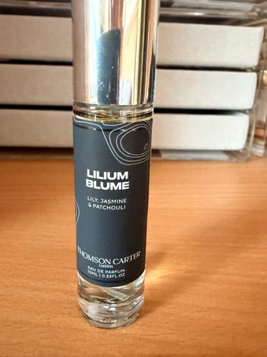 Customer's travel-size bottle of Lilium Blume Eau de Parfum on a wooden table.