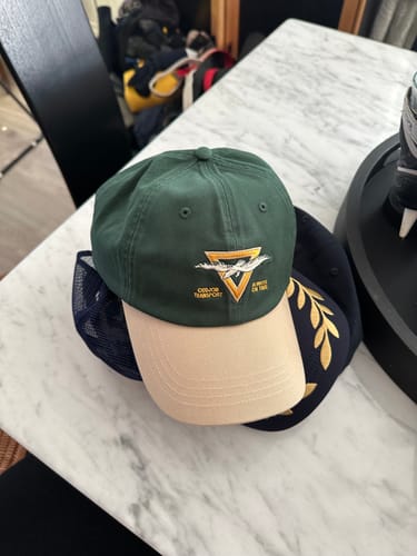 Customer's green and tan Big Dad Hat Two Tone sitting on a white marble table.