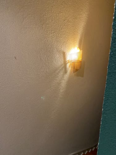 L'ampoule LED E14 du client, allumée dans une applique murale et projetant une lumière chaude.