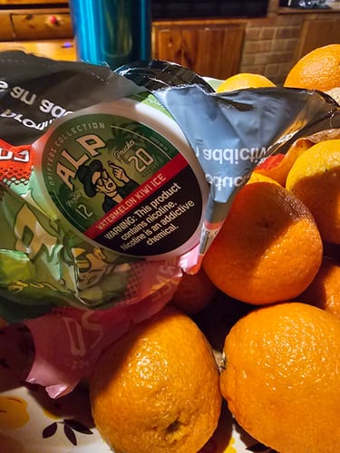 A customer's can of Drifters Watermelon Kiwi Ice nicotine pouches in a bag placed in a bowl with several oranges.