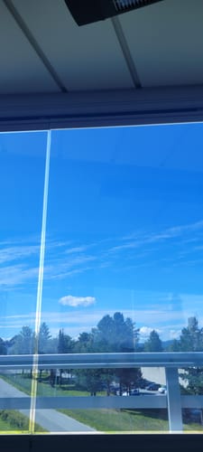 Kundens bilde av Static Reflektiv vindusfolie på en innglasset veranda, som viser en klar utsikt til en blå himmel.