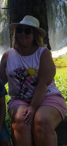 Customer wearing the Feral Girl Summer tank top while sitting outdoors near a waterfall.