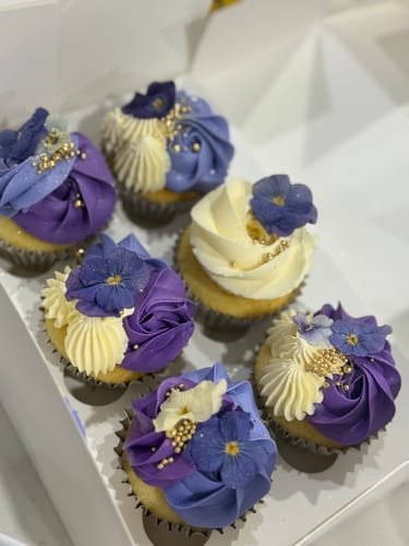 Customer shows six lovely cupcakes topped with purple and white freeze dried edible pansies.