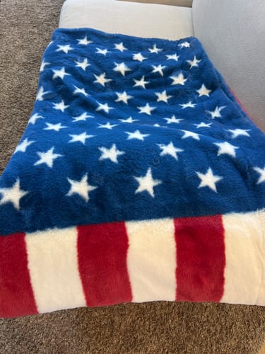 Customer's soft Lush Flag Blanket with an American flag design draped over a couch.