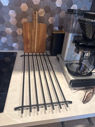 Kundens sorte gryterist plassert på en kjøkkenbenk ved siden av en kaffetrakter og et skjærebrett.