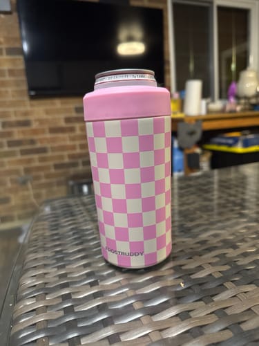 Customer's pink checkered Universal Buddy can cooler holding a beverage on a woven table.
