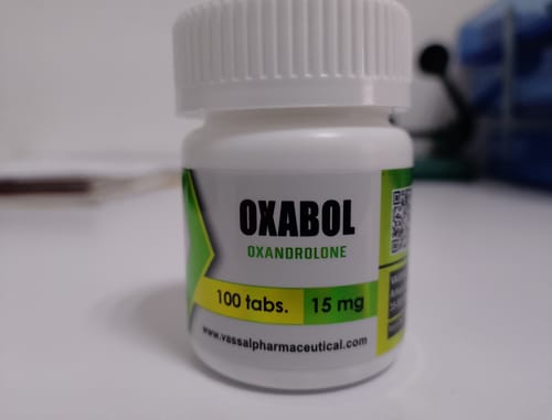 El cliente muestra un primer plano del frasco blanco de Oxabol 15 mg sobre una mesa.