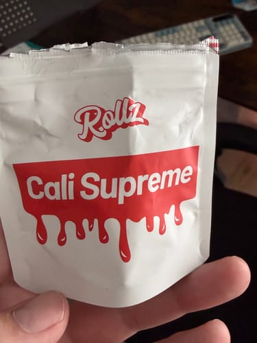 Customer holding the white and red packaging for CALI SUPREME THCA Flower.