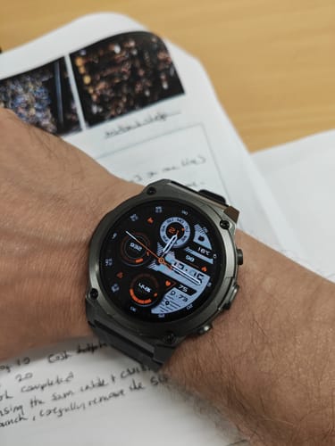Reviewer's dark smartwatch on their wrist, showing a digital fitness-tracking face.