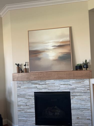 Customer's Sunlit Waters Canvas Art placed on a wooden mantle above a fireplace, showing its soft beige and cream tones.