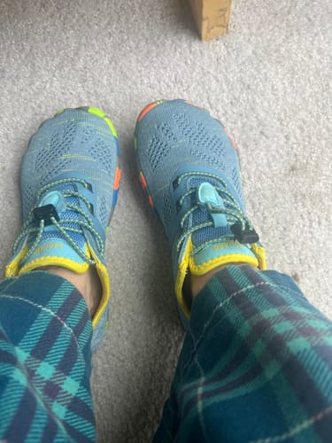 Reviewer wearing the blue Kid's Smart I Barefoot Shoes with colorful accents, seen from a top-down perspective.