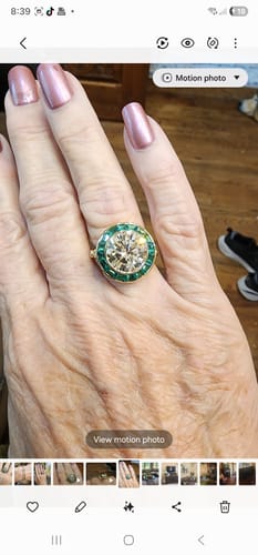 Reviewer's hand wearing the halo bezel engagement ring with a large center stone and a green halo.