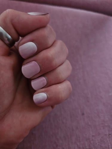 Rezensentin zeigt ihre Hand mit den manikürten „Blush Radiance“ UV-Gel-Nägeln mit sanftem rosa Farbverlauf.