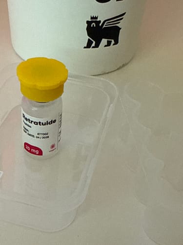 Cliente muestra un pequeño vial de 20 mg con tapa amarilla brillante.