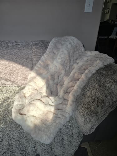 Customer's plush Hugs Cream Fawn Blanket shows its subtle pattern draped on a sofa.