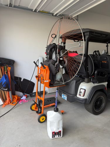 Customer's white 5 Gallon Jug with a spout on a garage floor, shown with a paramotor and a golf cart.