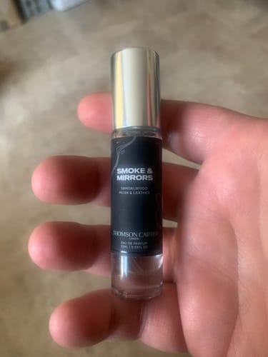 Reviewer holding a trial-size bottle of Smoke & Mirrors Eau de Parfum in their hand.
