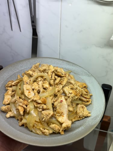 顧客手持盛滿洋蔥炒雞肉的灰色Vermicular斜邊淺碟。