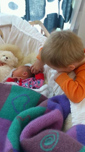 Anmelderens bilde av et barn som ser på en nyfødt baby.