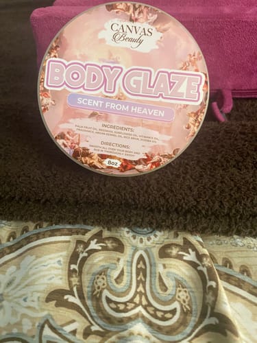 Customer's round container of Canvas Beauty Body Glaze in the Scent From Heaven, resting on a brown towel.