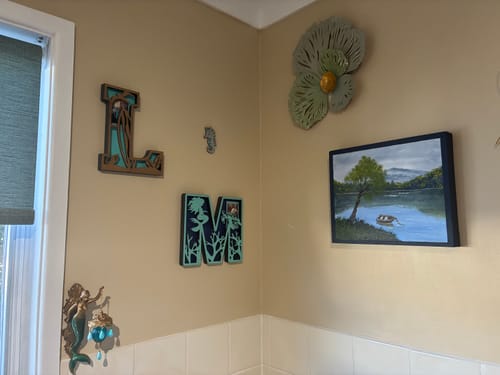 Customer's green Flower Metal Wall Art mounted high in the corner of a room with other wall decor.