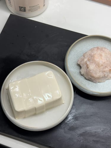 顧客將豆腐和肉滑分別放在兩個Vermicular弧邊淺碟上，準備打邊爐。