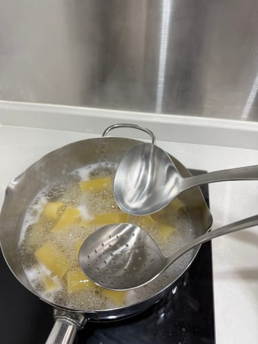 顧客在一個沸騰的鍋中使用柳宗理不鏽鋼湯勺煮通心粉。