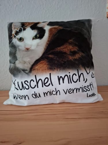 Rezensent zeigt ein personalisiertes Kissen mit dem Foto einer Katze und dem Spruch 'Kuschel mich, wenn du mich vermisst!'.