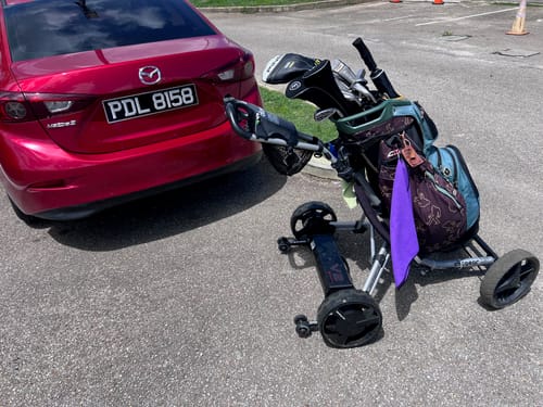 Customer's Club Booster V2Pro motorized unit shown detached from a golf cart in a parking lot.
