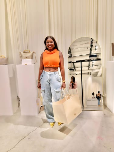 Customer wearing the orange Knit Sleeveless Braid Top with light-wash jeans.