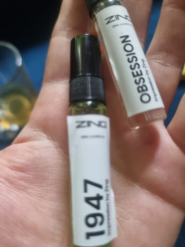 Close-up of a reviewer holding two small perfume samplers from the Summer Tester Pack in their hand.
