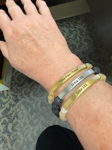 Customer's wrist with three stacked Citrine Custom Bracelets, engraved with 'Gma-143' and 'One-Four-Three'.