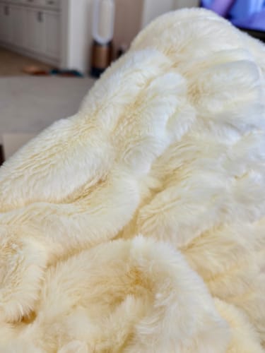 Close-up of a reviewer's soft, pale yellow Hugs Light Pear Blanket, showing its fluffy texture.